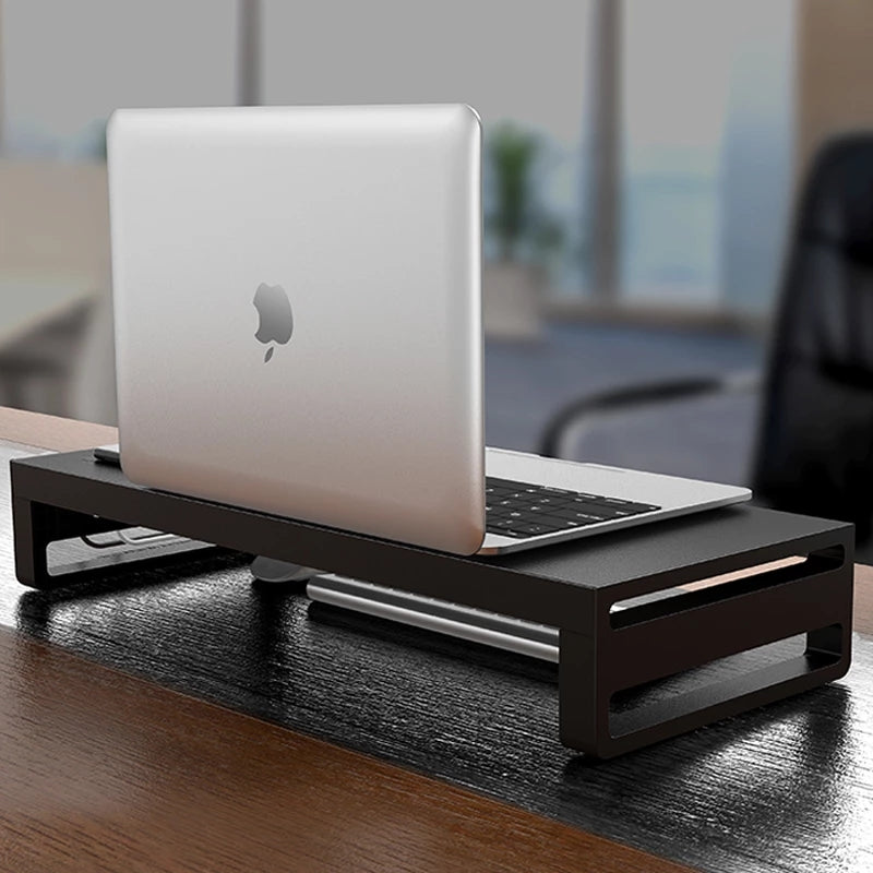 NOIRDEN Signature Monitor Riser on a dark wood desk with a MacBook resting on top in a minimal office setting