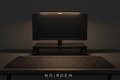 NOIRDEN Signature Trio bundle — Monitor Riser and Monitor Light on a dark minimal desk with desk mat, warm ambient glow